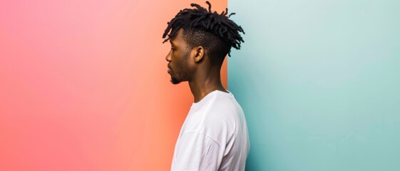 Obraz premium A young man stands against a colorful split background, with a thoughtful expression in profile, highlighting a modern and stylish aesthetic.