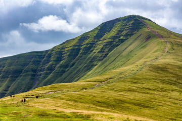 Hikers ascending Pen-y-Fan in the Brecon Beacons from the Cwm Gwdi ridge on the north side