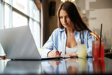 Front view. Beautiful woman with laptop is in the bar