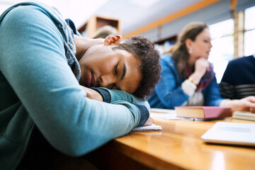 Man, student and sleep in library with group, burnout and tired with books, tech and education at college. Person, fatigue and exhausted with studying, learning and development in hall at university