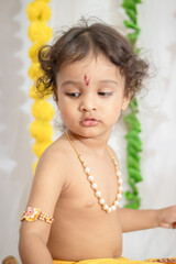 little indian baby boy in holy hindu god kirshna attire at indoor