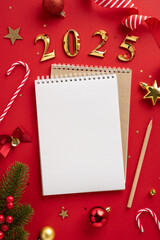 A festive vertical 2025 new year concept featuring a blank notebook surrounded by Christmas...