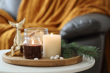 Burning candles, fir branches and decorative deer on coffee table indoors, space for text....