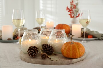 Burning candles and autumn decor on table indoors