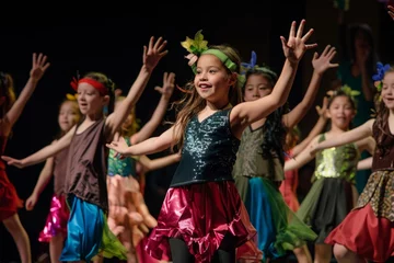 A group of young girls are singing and dancing on stage