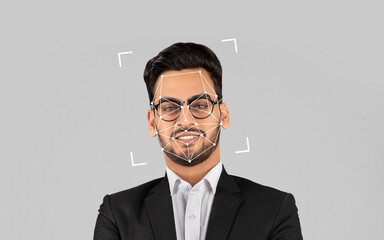 Eastern man in a suit stands confidently with a digital facial recognition overlay in a neutral background.