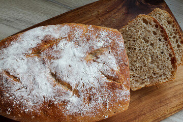 Whole grain bread laid out by the bakery chef on a kitchen wooden board. Fresh bread on the table close-up. 
