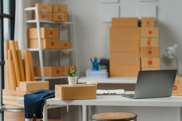 E-commerce Workspace: A Minimalist and Organized Home Office Scene for Small Business Owners. Laptop, Boxes, and a Plant create a calming atmosphere. 