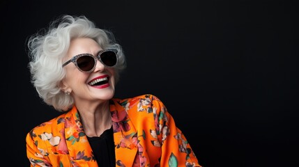 Obraz premium Joyful senior woman in vibrant orange outfit with sunglasses for spring fashion