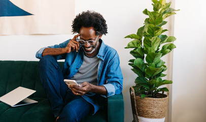 Mature man smiling and reading a message from his mobile phone at home