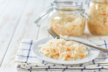 sauerkraut with carrot in a white bowl on the table, selective focus