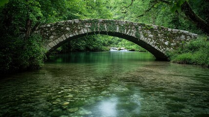 A stone footbridge with ivy growing along the sides, spanning a clear, shallow river.