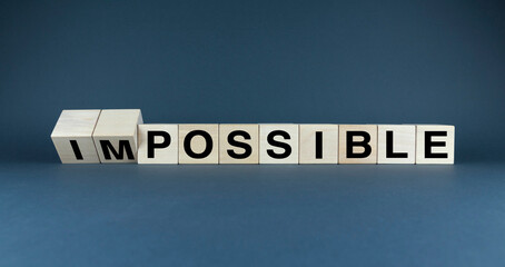 A minimalist image of wooden blocks arranged to form the words IMPOSSIBLE and POSSIBLE