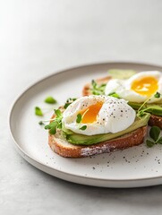 A plate of avocado toast topped with poached eggs and microgreens.