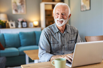 Senior man surfing on laptop at desk in apartment. Cropped shot of a senior man using his laptop while sitting at home.....