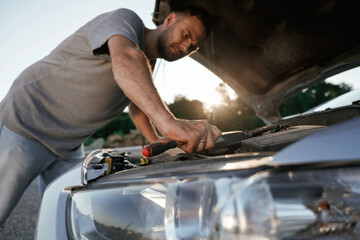 Breakdown, hood is opened, repairing. Man is with his car outdoors