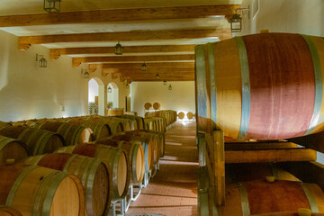 Large barrel of wine resting in a cellar in a large Italian wine estate.