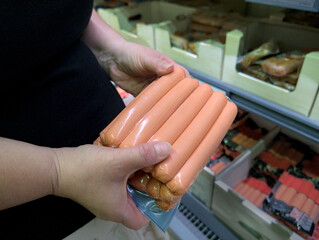 Clouse up shot of a womans hands holding a pack of  wursts in the supermaket, checking the product