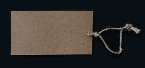 Blank brown tag with rustic thread string isolated on black background. Copy space.