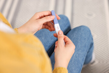 Woman holding pregnancy test in room, closeup