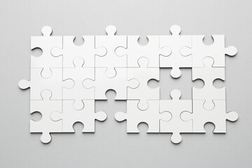 White puzzle pieces on grey background, top view