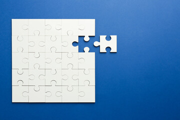 Fototapeta premium White puzzle pieces on blue background, top view