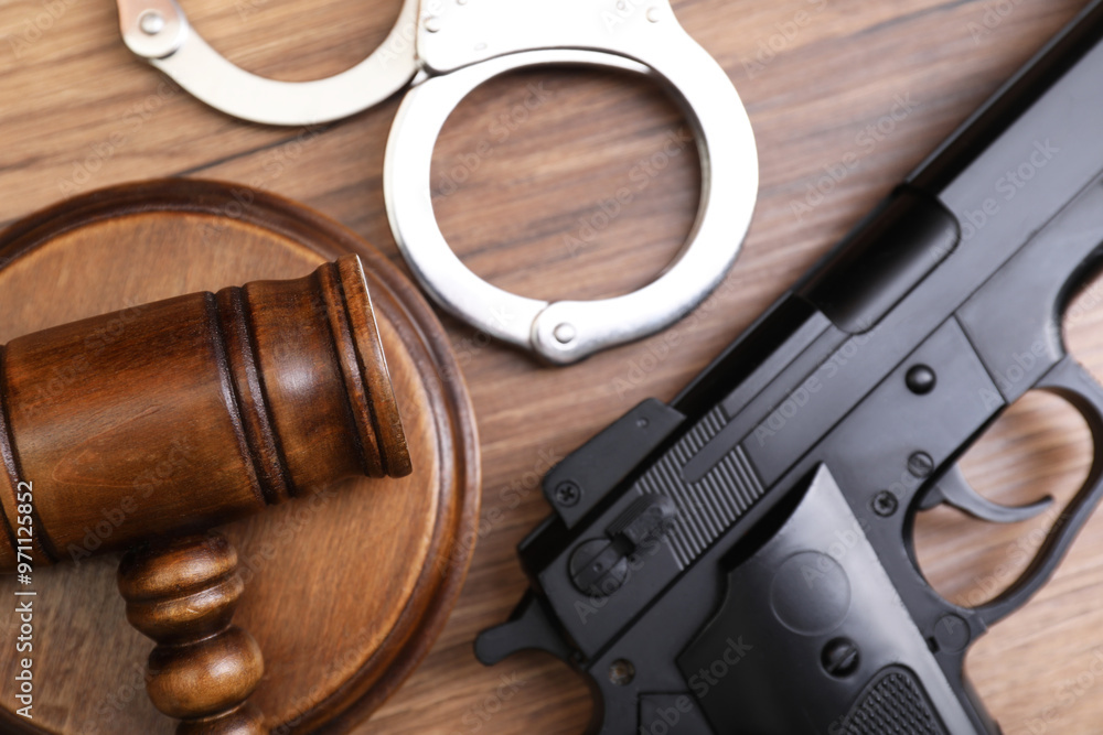 Wall mural judge's gavel, handcuffs and gun on wooden table, flat lay