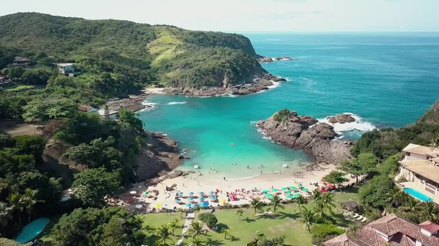 Aerial view of Praia da Ferradurinha in Buzios, surrounded by rocks and green hills.