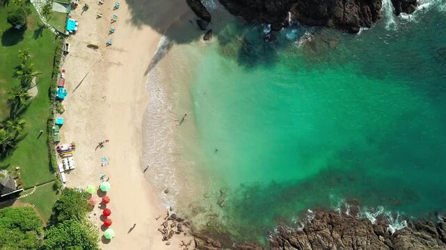 Aerial view of Praia da Ferradurinha in Buzios, featuring crystal-clear waters and umbrellas.