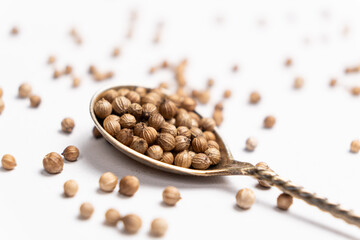 Coriander Grains in a Spoon on a White Background.