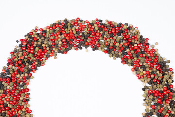 Frame of different varieties of peppercorns on a white background, top view, place for text.
