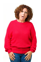 Beautiful middle ager senior woman red winter sweater over isolated background In shock face, looking skeptical and sarcastic, surprised with open mouth