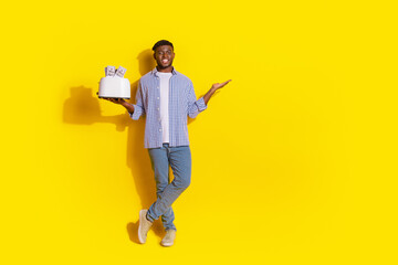 Full length photo of cheerful positive guy dressed checkered shirt toasting cash holding arm emtpy space isolated yellow color background
