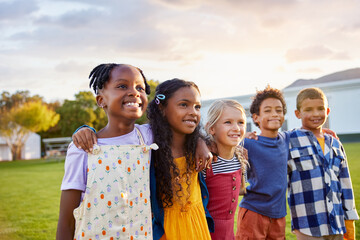 Happy multiethnic group of children hugging together at park