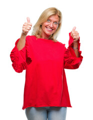 Middle age blonde woman over isolated background approving doing positive gesture with hand, thumbs...