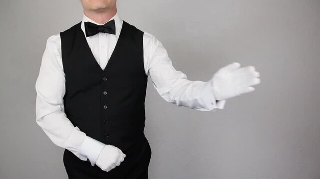 Butler or Waiter in Black Vest and White Gloves With Welcoming Gesture. Service Industry and Professional Hospitality.