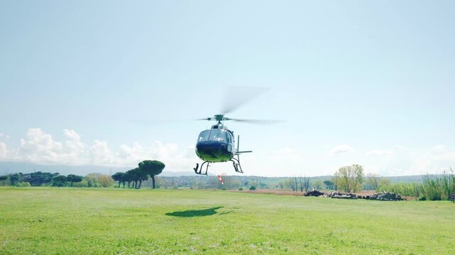 Helicopter with pilot and passengers landing on countryside field in sunny day, aircraft with rotating blades hovering above green lawn, helicopter flying experience concept