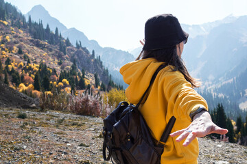 A young female tourist in a yellow hoodie on the background of nature,