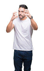 Fototapeta premium Young man wearing casual white t-shirt over isolated background Shouting frustrated with rage, hands trying to strangle, yelling mad