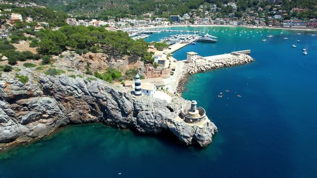 Aerial orbit flyover of Cap Gros lighthouse and Port de Soller bay Mallorca island Spain 4K