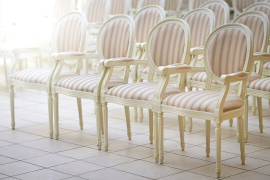 Elegant white chairs with striped upholstery arranged in perfect symmetry, serene and inviting atmosphere in stylish venue, special event or ceremony..