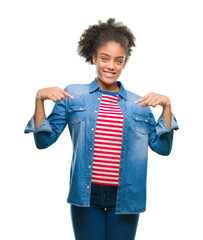 Young afro american woman over isolated background looking confident with smile on face, pointing...