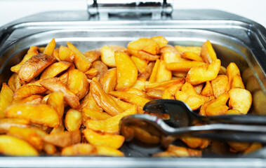 Baked potato slices in a metal tray.