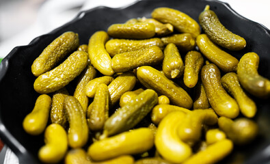 Lots of small pickled gherkins in a bowl.