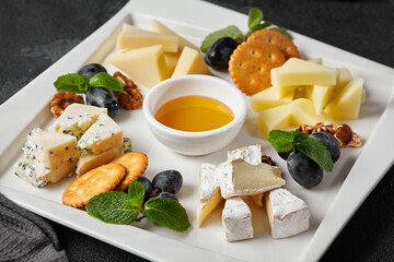 Elegant Cheese Platter with Assorted Cheeses, Honey, and Fruits on Dark Backdrop
