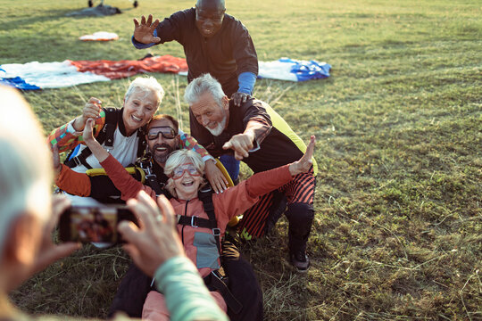 Group of senior friends taking skydiving celebration photo after landing