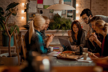 Diverse students eating pizza while studying together at home