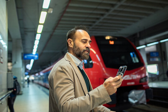 Businessman checking smartphone at the train station