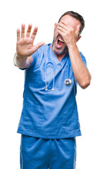 Fototapeta premium Middle age hoary senior doctor man wearing medical uniform over isolated background covering eyes with hands and doing stop gesture with sad and fear expression. Embarrassed and negative concept.