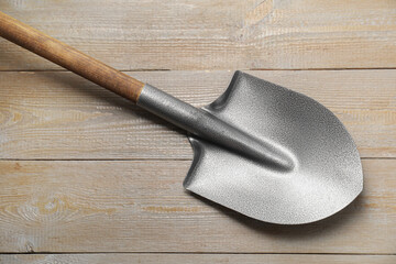 Metal shovel on light wooden table, top view